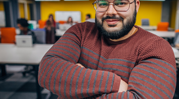 photo of man with beard and glasses in an office setting, looking happy