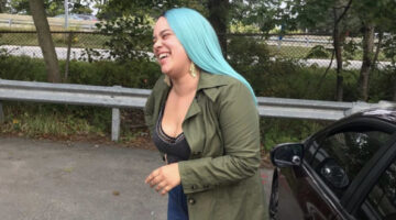 Black femme with light skin and long blue hair smiling and laughing