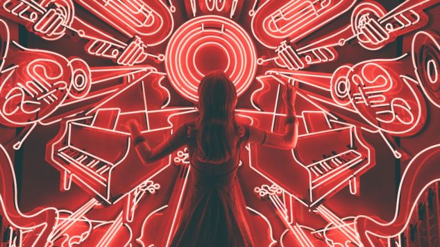 Person in dress standing with their back to camera, conducting a chaotic pattern of red neon instruments.